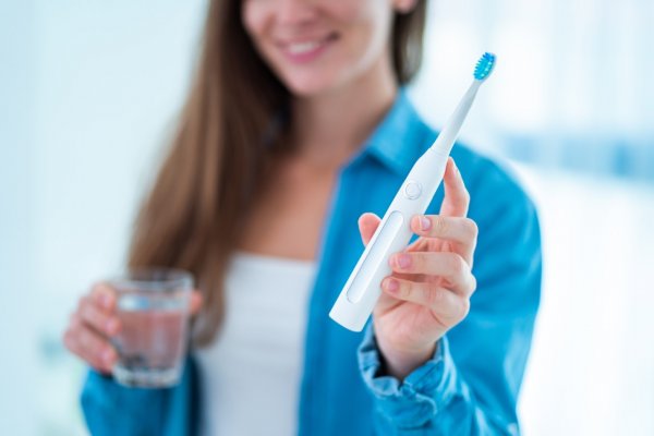 woman holding electric toothbrush